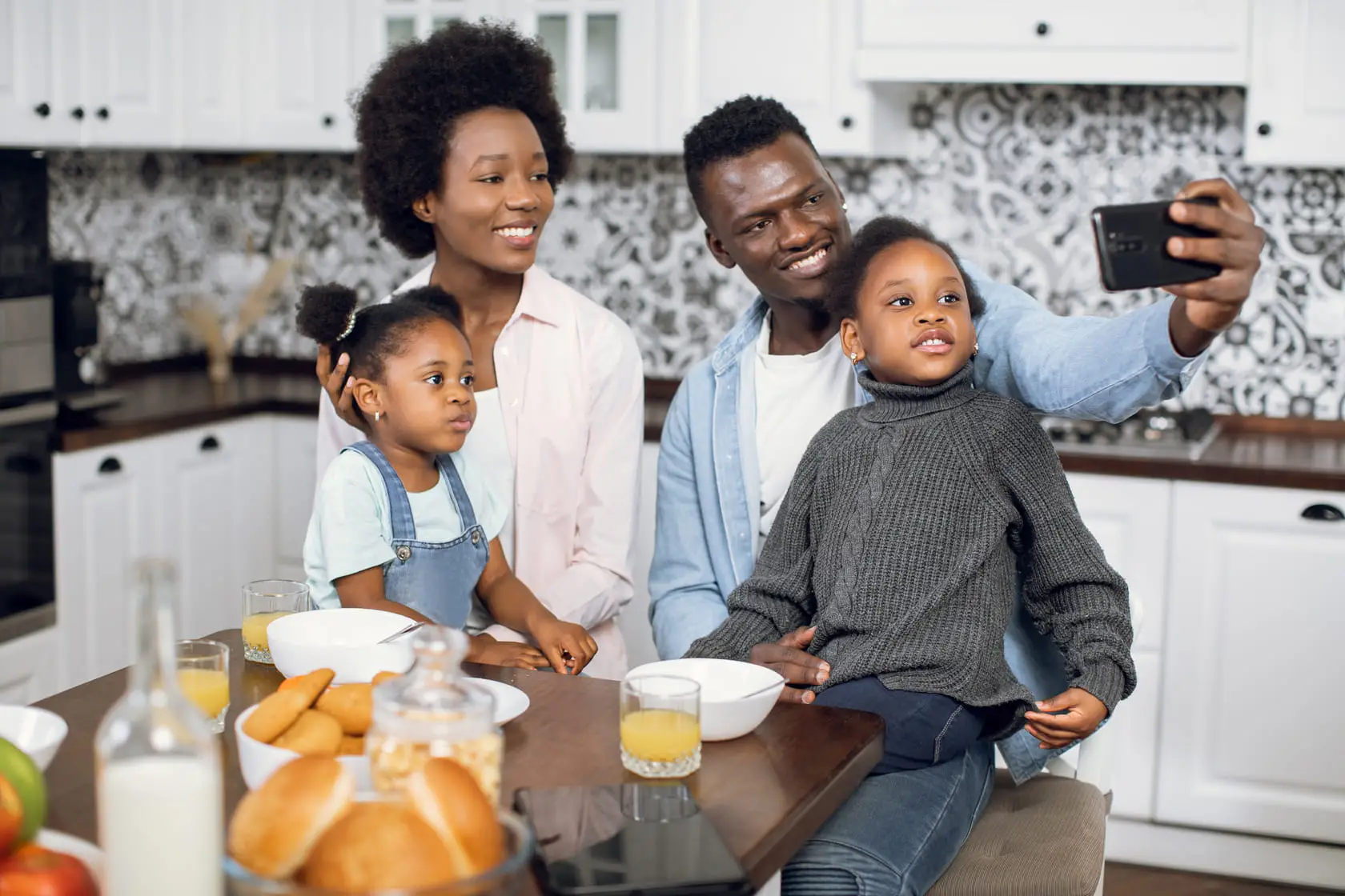 Famille africaine prenant une photo avec leur mobile en compagnie de leur fille